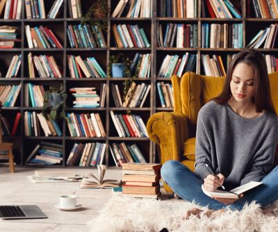 eine junge Frau sitzt auf dem Boden ihrer Hausbibliothek und macht sich Notizen langste Wort der Welt skrivanek