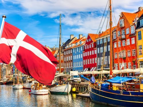 Der beruhmte alte Hafen Nyhavn im Zentrum von Kopenhagen,an einem sonnigen Sommertag mit der danischen Flagge im Vordergrund hallo auf danisch skrivanek