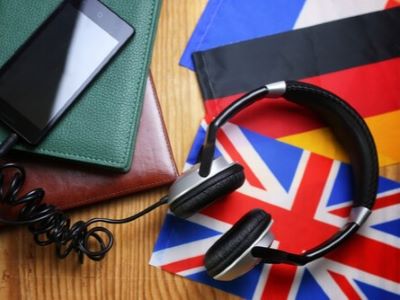 Kopfhorer, Smartphone und Notebooks auf einem Tisch mit britischen und deutschen Flaggen deutsche Worter im Englischen skrivanek