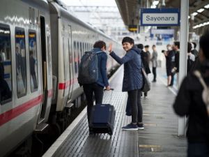 Zwei Personen auf einem Bahnsteig, eine davon winkt, wahrend sie in einen Zug einsteigen hallo auf japanisch skrivanek