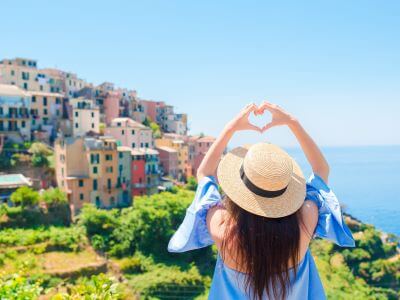 Eine Frau mit Strohhut formt ein Herz mit den Handen Meer im Hintergrund danke auf italienisch ubersetzungsburo berlin