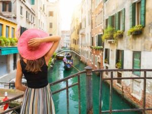 Eine elegante Frau mit einem roten Hut genießt den Blick auf den Kanal in Venedig Italien hallo auf italienisch ubersetzungsburo berlin