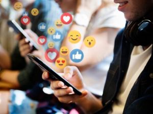 Person mit Smartphone und schwebenden Emojis symbolisiert Social Media Interaktion betende hande ubersetzungsburo berlin