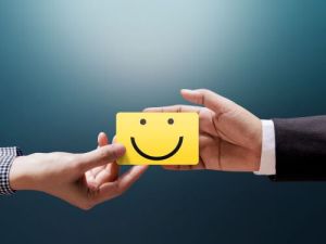 Zwei Hande tauschen eine gelbe Karte mit einem lachelnden Gesicht aus betende hande ubersetzungsburo berlin