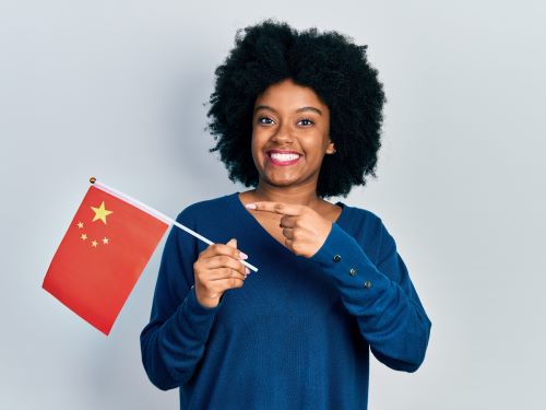 Junge afroamerikanische Frau halt China Flagge lachelnd glucklich hallo auf Chinesisch Ubersetzugnsburo Berlin