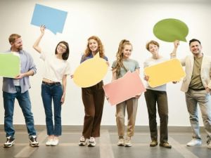 Sechs lächelnde Personen halten bunte Sprechblasen und stehen nebeneinander Was ist die einfachste Sprache der Welt Übersetzungsbüro Berlin Sechs lachelnde Personen halten bunte Sprechblasen und stehen nebeneinander Was ist die einfachste Sprache der Welt Ubersetzungsburo Berlin