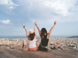 Zwei junge Frauen genießen die Aussicht über Barcelona und symbolisieren die Freiheit und Abenteuerlust beim Auswandern nach Spanien Ubersetzungsburo Berlin