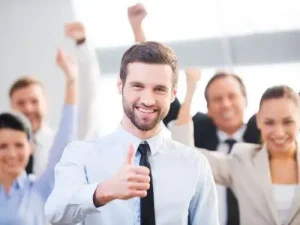 Mann im Anzug zeigt Daumen hoch, Team im Hintergrund jubelt Erfolgsmoment im Stil eines High Five Emoji Ubersetzungsburo Berlin