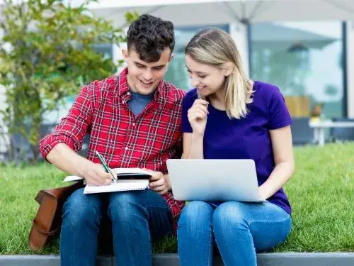 Two students studying outdoors and researching the easiest languages to learn for German speakers Ubersetzungsburo Berlin